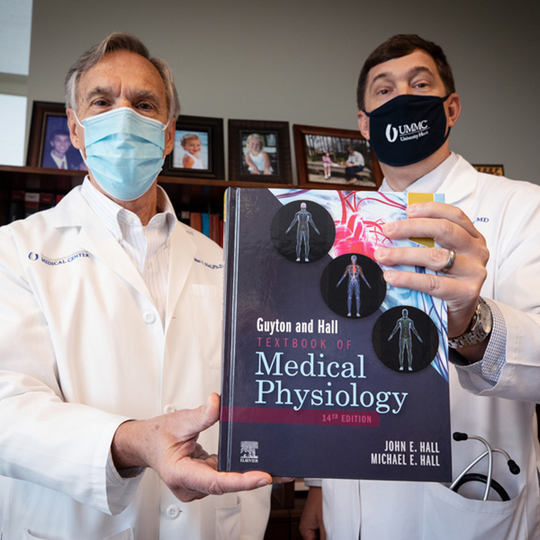 Dr. John Hall and his son Dr. Michael Hall hold the medical textbook they have updated