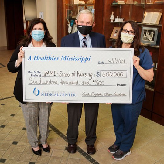 Three people holding a giant check 