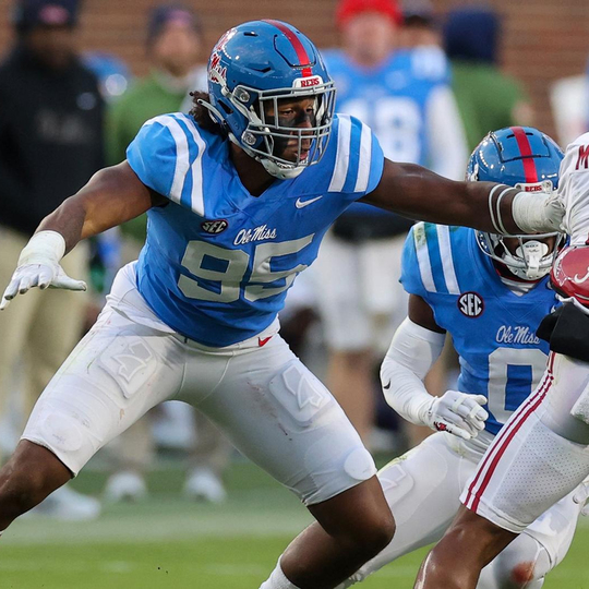 Ole Miss Player number 95 with his hand on the opponent jersey in powder blue uniform